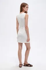 Vestido corto blanco de viscosa, sin mangas, con cuello redondo a la base y bolsillos frontales con apliques bordados.
