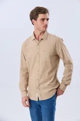 Camisa de lino de manga larga en color beige, con cuello camisero, cierre frontal de botones y un bolsillo ojal en el pecho.
