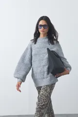 Sweater de punto con textura tramada, color azul marino, de silueta relajada y mangas abullonadas con puños ajustados.