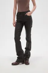 Pantalon de corte flare en color negro, con acabado engomado, tiro medio y cierre frontal con botón y cremallera.