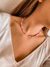 Gargantilla de cuentas pequeñas de colores rosa, naranja y dorado.