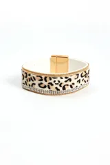 Brazalete rígido con estampado animal print de leopardo, borde superior e inferior con cadena dorada y línea de strass. Cierre magnético dorado.