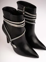 Botines plateados con terminación en punta y taco aguja. Decorados con tiras de strass que se enrollan alrededor del tobillo y se atan en el empeine.