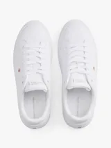 Zapatillas de tenis de corte bajo de la marca Tommy Hilfiger, confeccionadas en piel napa de color blanco. Presentan cordones, punta redonda, suela de goma y detalles distintivos como un pequeño logo esmaltado en el lateral y el nombre de la marca en la lengüeta.