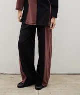 Pantalón de corte recto y holgado, confeccionado en algodón con diseño bicolor en bloques de color negro y bordó, con costuras visibles a contraste.