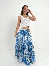 Falda larga de algodón con estampado floral en tonos azul y blanco. Tiene elástico en la cintura y viene con un cinto de rafia elastizado, desmontable.
