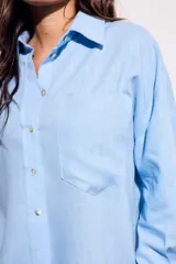 Camisa oversize de lino y viscosa color celeste, con cuello clásico, cierre frontal con botones y mangas largas.