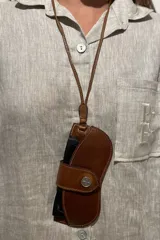 Cuelga lentes de cuero rojo con correa fina y botón metálico.