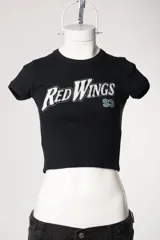 Remera tipo baby tee blanca de manga corta, con cuello redondo y diseño ajustado al cuerpo con estampado y bordado frontal "Red Wings 93".