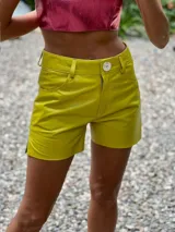 Shorts de cuero color verde de tiro medio y corte recto, con cierre frontal, botón y bolsillos funcionales.