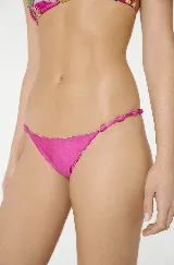 Conjunto de bikini Blueman fucsia con estampado de palmeras y tucanes. El corpiño es de triángulo con tiras trenzadas y detalle dorado en el centro. La bombacha es tipo colaless con tiras trenzadas a los costados.