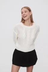 Sweater de punto color celeste, con diseño de trenzas frontales, cuello redondo y corte holgado.