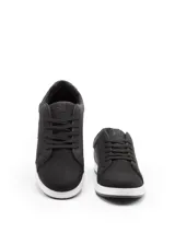 Zapatilla urbana de caña baja, color blanco, con cordones blancos. Presenta paneles laterales con perforaciones y un detalle de refuerzo en el talón de color negro.