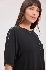 Remera negra de corte recto con cuello redondo y bolsillo en el pecho. Detalles de tachas plateadas en cuello, mangas y bolsillo.