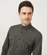 Camisa verde militar de manga larga en sarga de algodón, con cuello clásico, cierre frontal abotonado y dos bolsillos con solapa abotonada en el pecho.