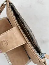 Billetera mediana de cuero color marrón con apliques dorados y cierre superior. Tiene correa de muñeca y bolsillo frontal con cierre de broche con logo de búho.
