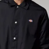 Campera tipo coach jacket de la marca Dickies, color negro, con cierre frontal de botones a presión, cuello clásico, puños elásticos y logo pequeño de la marca en el pecho.