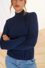 Sweater rojo de punto con cuello alto y mangas largas. Presenta detalles de costuras verticales en color azul en la parte delantera y en los hombros.