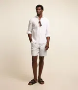 Bermuda básica masculina de sarga color gris, con trabillas en la cintura, cierre tradicional de botón y cremallera, y bolsillos funcionales.