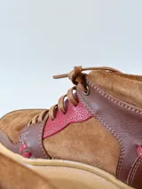 Zapatillas acordonadas de cuero marrón con detalles en rojo y suela de goma color caramelo.