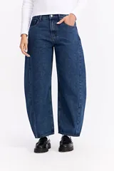 Jean de tiro alto con silueta amplia y redondeada tipo balloon, confeccionado en denim de algodón azul oscuro con costuras verticales decorativas.