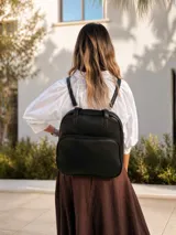 Mochila versátil convertible en cartera, color beige con detalles en marrón. Cuenta con doble asa superior, correas ajustables y desmontables, bolsillo frontal con cierre y compartimento principal amplio.