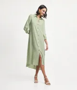 Vestido chemise largo color verde menta, confeccionado en viscolino de marca Marfinno. Presenta cuello solapa, cierre frontal de botones contrastantes, manga larga con trabilla (martingale) y aberturas laterales en el bajo.
