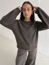 Sweater de punto color gris con cuello redondo, mangas largas y terminaciones con detalle de pespunte en color crudo en el cuello, puños y ruedo.