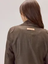 Blazer de denim estructurado con solapas clásicas, cierre frontal de un botón y bolsillos laterales con solapa. Presenta costuras visibles en contraste y un corte sastrero.