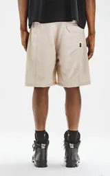 Bermuda color beige de calce relax-fit, con cintura elástica y cordón de ajuste negro. Presenta grandes bolsillos cargo con fuelle en las piernas y un cinturón de cinta negra con hebilla de plástico.