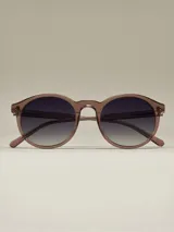 Lentes de sol de montura redonda en tono marrón rosado translúcido, con lentes oscuros degradados de negro a gris claro.