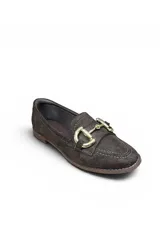 Mocasín de gamuza color beige, con detalle de hebilla metálica dorada en el empeine, costuras visibles y suela plana.