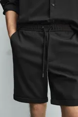 Bermuda regular fit de tejido elástico color blanco, con cintura elástica ajustable mediante cordón, bolsillos delanteros y bolsillos traseros de vivo.