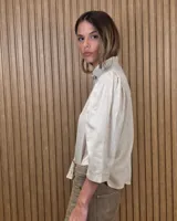 Camisa de algodón color blanco, con cuello alto con volados, mangas tres cuartos con detalles de bordado ingles y cierre frontal con botones de nácar.