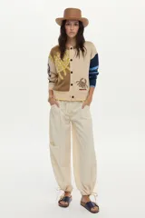 Cardigan de punto con ilustraciones en jacquard y detalle bordado en el frente, mangas largas con puños acanalados, escote redondo y cierre frontal de botones.