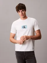 Remera de algodón de corte regular, color beige, con cuello redondo y estampa frontal con el monograma de Calvin Klein sobre un recuadro celeste.