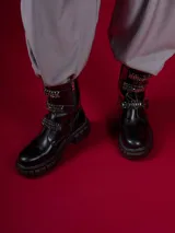 Botas negras de caña baja con suela track, cierre lateral y detalles de hebillas con tachas y cadenas.