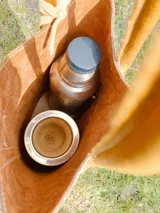 Bolso matero de cuero color chocolate con textura croco, asas cortas y detalle de costuras en los laterales. Incluye un dije con flecos en tonos beige y negro.