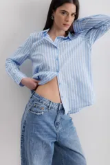 Camisa de manga larga con diseño de rayas verticales en tonos azul y blanco, cuello clásico y cierre frontal con botones.