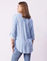 Camisa celeste con rayas verticales blancas, de corte recto y manga 3/4 regulable con presilla y botón.