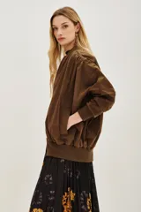 Campera bomber de corte holgado en color marrón, con cuello, puños y ruedo de tejido elástico acanalado. Presenta cierre frontal y diseño de mangas con volumen.