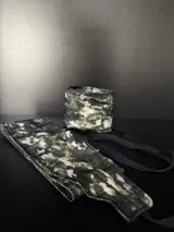 Muñequeras deportivas con estampado camuflado en tonos verdes, grises y blancos. Cuentan con un diseño de ajuste mediante cintas elásticas negras.