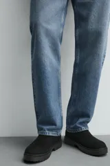 Bota estilo Chelsea de hombre, fabricada en piel con acabado de serraje. Presenta elásticos laterales, horma redonda y suela con ligero tacón.