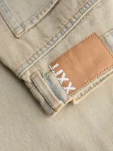 Jean de corte barrel fit con tiro medio, confeccionado en denim de sarga con un lavado teñido en tono beige. Presenta pierna suelta, cierre con bragueta y diseño de cinco bolsillos.