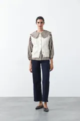 Chaleco tejido de punto color marrón oscuro, con botones frontales y diseño de punto calado vertical.