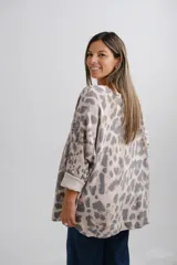 Sweter de punto con escote en V y mangas largas con puños vueltos. Presenta un diseño holgado con estampado animal print en tonos neutros.