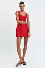 Vestido corto de color rojo con escote corazón estilo corsetero, tirantes anchos y falda con corte evasé. Cuenta con cierre de cremallera oculto en la espalda.