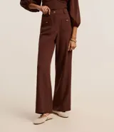 Pantalón sastrero marrón de corte recto y cintura alta, con trabillas en la cintura, bolsillos delanteros y traseros simulados, cierre tradicional y botones metalizados.