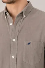 Camisa de pana verde oscuro de corte clásico, con cuello button-down, cierre frontal de botones, bolsillo en el pecho con detalle bordado y mangas largas.