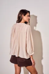 Blusa de manga larga con diseño a rayas verticales, cuello redondo con pequeña abertura frontal abotonada y mangas con puños elásticos.